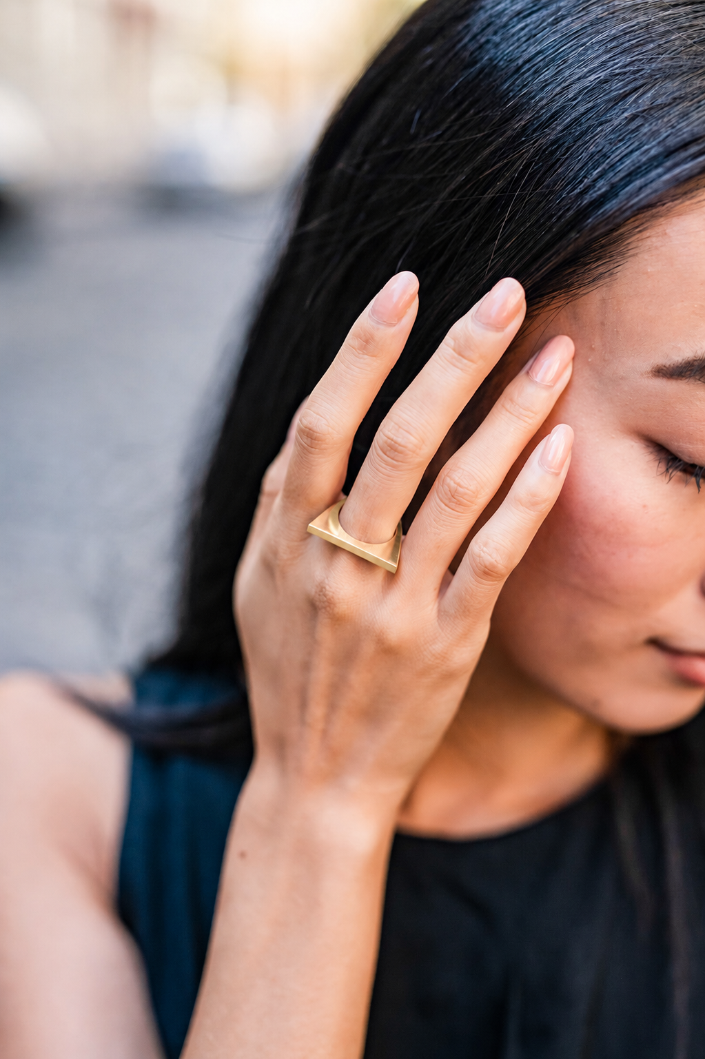 Woman wearing a gold Knockout ring on her finger with a blurred background